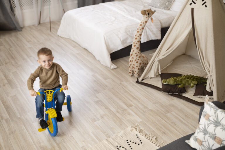 full-shot-happy-kid-sitting-tricycle-indoors